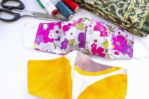 cloth mask or fabric face mask with cotton fabric flower pattern handmade crafts isolated on white background. This hygienic mask for cover mouth and protection with beautiful sewing fashion. photo
