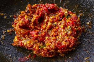 sambal fresco servido en cobek de mortero de piedra. sambal es una salsa tradicional de indonesia hecha de chili foto