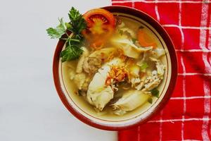 Chicken soup served with vegetables, tomatoes, celery in a bowl, spoon and fork. with black background photo