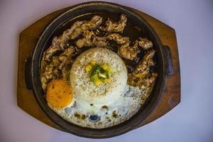 breakfast with rice, fried egg and meat or beef with garnish corn and leek close up hot plate isolated on white background photo