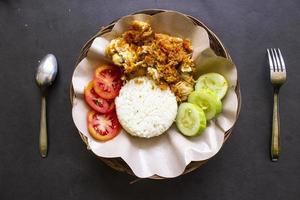 ayam geprek or chicken crush or chicken smashed is indonesian food made from made fried chicken pounded with chilli and garlic flavour and served with vegetables and rice photo