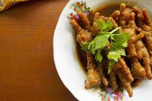Spicy chicken feet with celery, chili, onion, garlic served with a white plate isolated from a black background. photo