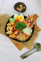 laksa, laksa curry made from vermicelli, noodles, bean sprouts, egg, tofu lime, and shrimp with a spicy soup sauce that is rich in spices. laksa served on bowl, isolated on white background. photo