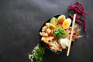 laksa, laksa curry made from vermicelli, noodles, bean sprouts, egg, tofu lime, and shrimp with a spicy soup sauce that is rich in spices. laksa served on bowl, isolated on white background. photo