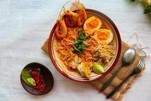 laksa, laksa curry made from vermicelli, noodles, bean sprouts, egg, tofu lime, and shrimp with a spicy soup sauce that is rich in spices. laksa served on bowl, isolated on white background. photo
