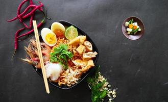 laksa, laksa curry made from vermicelli, noodles, bean sprouts, egg, tofu lime, and shrimp with a spicy soup sauce that is rich in spices. laksa served on bowl, isolated on white background. photo
