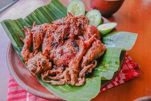 pollo a la parrilla o ayam bakar con pepino servido en hoja de plátano y plato. ayam bakar es pollo asado tradicional de indonesia foto