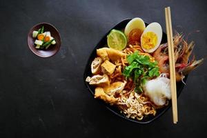 laksa, laksa curry made from vermicelli, noodles, bean sprouts, egg, tofu lime, and shrimp with a spicy soup sauce that is rich in spices. laksa served on bowl, isolated on white background. photo