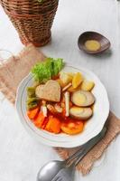 selat solo is traditional salad food from indonesia. made from hard-boiled eggs, boiled chickpeas, boiled carrots, hash browns and lettuce, steak or bistik. served on wood table photo