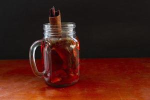 wedang uwuh is traditional herbal drink from indonesia. made from cinnamon, nutmeg and cloves leaves. Another ingredient is wood from the secang tree, ginger and lump sugar on black background photo