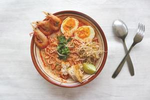 laksa, laksa curry made from vermicelli, noodles, bean sprouts, egg, tofu lime, and shrimp with a spicy soup sauce that is rich in spices. laksa served on bowl, isolated on white background. photo