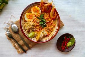 laksa, laksa curry made from vermicelli, noodles, bean sprouts, egg, tofu lime, and shrimp with a spicy soup sauce that is rich in spices. laksa served on bowl, isolated on white background. photo