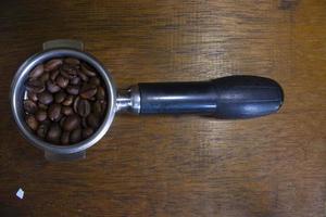porta filtro con café molido y granos de café en la mesa foto