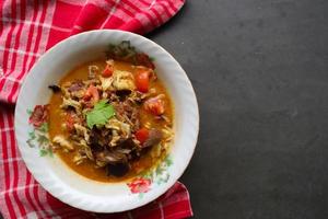 Goat Curry or gulai kambing, food from asia. Delicious goat meat curry served in a bowl.served with tomato, seasoning, celery and cabbage photo