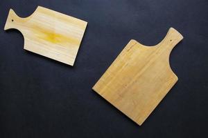 tabla de cortar de madera para cocinar. tabla de cortar de madera sobre fondo negro. vista superior con espacio de copia para texto. menú, receta, maqueta plana, fondo de banner foto