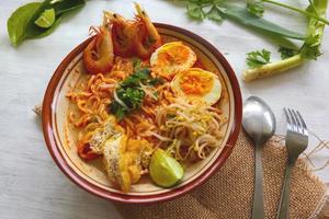 laksa, laksa curry made from vermicelli, noodles, bean sprouts, egg, tofu lime, and shrimp with a spicy soup sauce that is rich in spices. laksa served on bowl, isolated on white background. photo