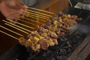 sate kambing o satay de cabra, cordero, cordero o carne de cabra satay con ingrediente de carbón en fuego rojo asado por personas. satay tradicional de yogyakarta, java, indonesia satay de cocina foto