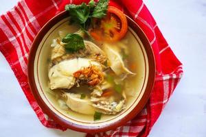 Chicken soup served with vegetables, tomatoes, celery in a bowl, spoon and fork. with black background photo