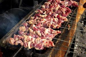 sate klatak o sate kambing o satay de cabra, cordero, cordero o carne de cabra satay con ingrediente de carbón en fuego rojo asado por personas, indonesia cocinando satay. con enfoque selectivo