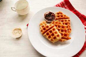 gofre croissant o croffle con salsa de chocolate servido en caja y fondo blanco foto