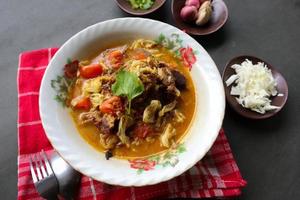 Goat Curry or gulai kambing, food from asia. Delicious goat meat curry served in a bowl.served with tomato, seasoning, celery and cabbage photo