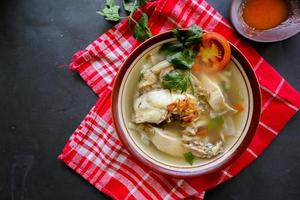 Chicken soup served with vegetables, tomatoes, celery in a bowl, spoon and fork. with black background photo