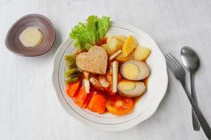 selat solo is traditional salad food from indonesia. made from hard-boiled eggs, boiled chickpeas, boiled carrots, hash browns and lettuce, steak or bistik. served on wood table photo
