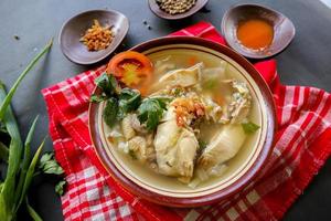 Chicken soup served with vegetables, tomatoes, celery in a bowl, spoon and fork. with black background photo