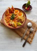 laksa, laksa curry made from vermicelli, noodles, bean sprouts, egg, tofu lime, and shrimp with a spicy soup sauce that is rich in spices. laksa served on bowl, isolated on white background. photo