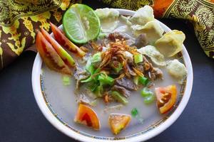 sop kaki kambing a traditional food from Betawi, Jakarta Indonesia, made from mutton or lamb, offal, spices. isolated on black background.This food is like lamb stew on black background photo