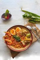 laksa, laksa curry made from vermicelli, noodles, bean sprouts, egg, tofu lime, and shrimp with a spicy soup sauce that is rich in spices. laksa served on bowl, isolated on white background. photo