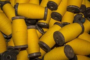 large grup yellow yarn on wood spool, yarn on tube, a collection of yellow threads on spool, which will be fabricated. yellow string. yellow thread. photo
