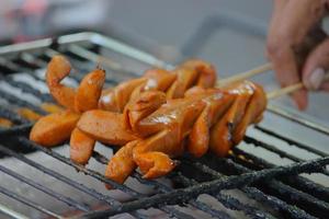 grilled sausage or sosis panggang on grill in the street food. selective focus photo