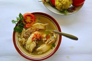 Chicken soup served with vegetables, tomatoes, celery in a bowl, spoon and fork. with black background photo