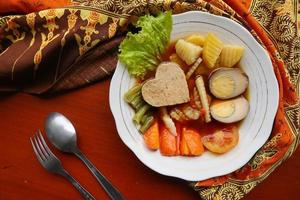 selat solo is traditional salad food from indonesia. made from hard-boiled eggs, boiled chickpeas, boiled carrots, hash browns and lettuce, steak or bistik. served on wood table photo