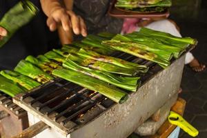 otak - otak is a food made from minced mackerel fish meat wrapped in banana leaves, baked, and served with spicy and sour sauce. otak-otak is traditional fish cake from indonesia photo