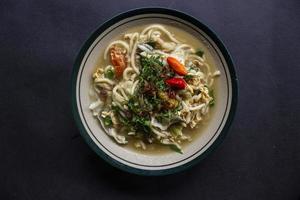 Mie godog Jawa or bakmi jawa or java noodle or Mie rebus or boiled noodles with spoon and fork. Indonesian traditional street food noodles from java, indonesia on white backgroud photo