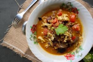 Goat Curry or gulai kambing, food from asia. Delicious goat meat curry served in a bowl.served with tomato, seasoning, celery and cabbage photo