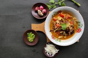 Goat Curry or gulai kambing, food from asia. Delicious goat meat curry served in a bowl.served with tomato, seasoning, celery and cabbage photo