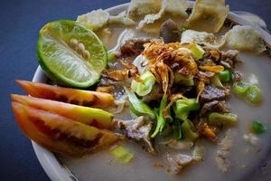 sop kaki kambing a traditional food from Betawi, Jakarta Indonesia, made from mutton or lamb, offal, spices. isolated on black background.This food is like lamb stew on black background photo