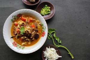 Goat Curry or gulai kambing, food from asia. Delicious goat meat curry served in a bowl.served with tomato, seasoning, celery and cabbage photo