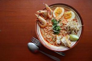 laksa, laksa curry made from vermicelli, noodles, bean sprouts, egg, tofu lime, and shrimp with a spicy soup sauce that is rich in spices. laksa served on bowl, isolated on white background. photo