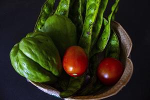 tropical tomatoes with jipang or labu siam or chayote and onion are served in a basket isolated on black background photo