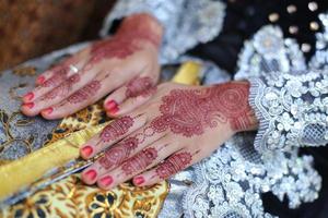 henna tattoo being applied on a women's hand. photo