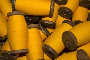 large grup yellow yarn on wood spool, yarn on tube, a collection of yellow threads on spool, which will be fabricated. yellow string. yellow thread. photo