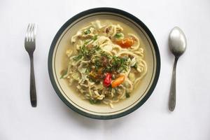 Mie godog Jawa or bakmi jawa or java noodle or Mie rebus or boiled noodles with spoon and fork. Indonesian traditional street food noodles from java, indonesia on white backgroud photo