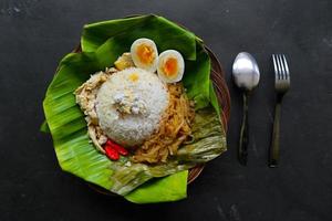 Nasi Liwet Solo or Sego Liwet Solo is a traditional food from Surakarta. made from savory rice, chayote and boiled egg, chicken, thick coconut milk served on a banana leaf photo