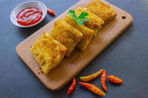 los risoles fritos o la mayonesa de risol son bocadillos indonesios. como coxinha de galinha. servido con salsa picante, apio sobre tabla de madera foto