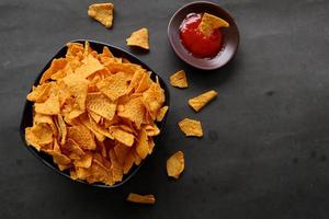 tortilla chip is corn chips or call nachos, served in bowl, on black background made from corn photo