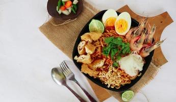 laksa, laksa curry made from vermicelli, noodles, bean sprouts, egg, tofu lime, and shrimp with a spicy soup sauce that is rich in spices. laksa served on bowl, isolated on white background. photo